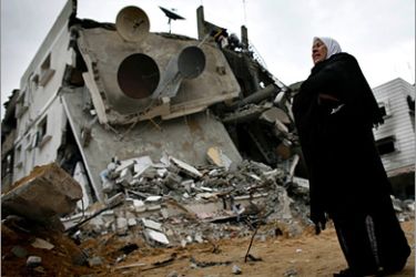 AFP / A Palestinian woman walks past destroyed buildings in Jabalia northern Gaza Strip on January 20 2009. Israel will cooperate with reconstruction efforts in the Gaza Strip only if