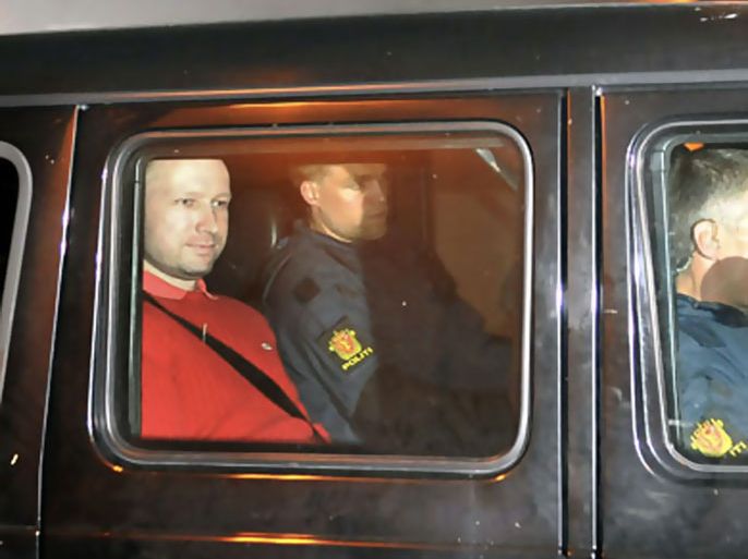 Bomb and terror suspect Anders Behring Breivik (red top) leaves the courthouse in a police car in Oslo on July 25, 2011, after the hearing to decide his further detention. Breivik will be held in solitary confinement for the first four weeks, with a ban on all communication with the outside world in a bid to aid a police investigation into his acts.