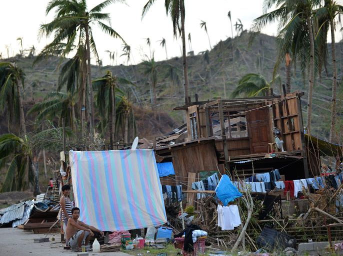 TA08 - Boston, -, PHILIPPINES : Residents stand next to their makeshift shelter and damaged house along a highway in Boston town, Davao Oriental province on December 10, 2012. The United Nations launched a 65 million USD global appeal on December 10 to help desperate survivors of a typhoon that killed more than 600 people and affected millions in the southern Philippines. AFP PHOTO/TED ALJIBE