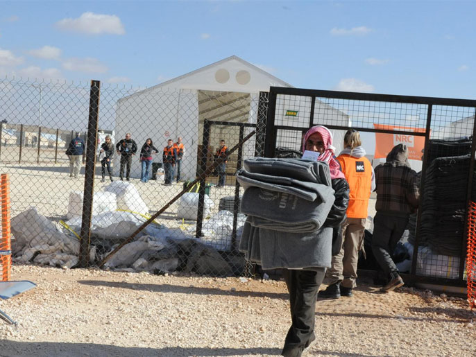 ‪لاجئ سوري يحمل بطانيات استلمها لأسرته‬ (الجزيرة نت)