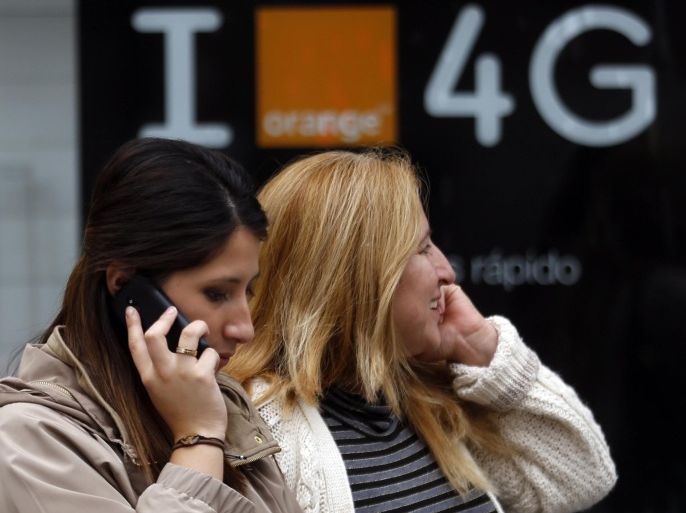 Women talk on mobile phones in front of an advertisement for 4G services in central Madrid, September 30, 2013. REUTERS/Sergio Perez