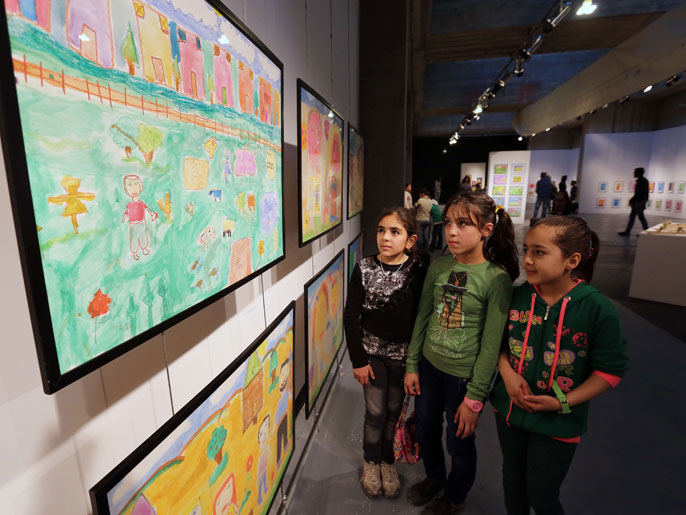أطفال من اللاجئين السوريين في لبنان يتأملون اللوحات التي رسمها أقرانهم (الفرنسية)