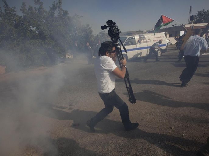Palestinian journalists run from a sound grenade thrown by Israeli soldiers during a demonstration calling for freedom of movement between West Bank cities for Palestinian journalists on World Press Freedom day, at the Israeli checkpoint of Beit El near the West Bank city of Ramallah, Saturday, May 3, 2014. (AP Photo/Majdi Mohammed)