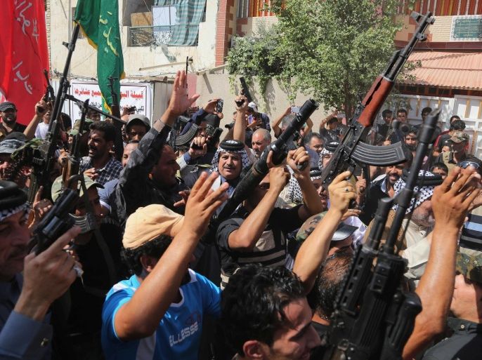 Iraqi Shiite tribal fighters raise their weapons and chant slogans against the al-Qaida inspired Islamic State of Iraq and the Levant (ISIL) in Baghdad's Sadr city, Iraq, Saturday, June 14, 2014. Thousands of Shiites from Baghdad and across southern Iraq answered an urgent call to arms Saturday, joining security forces to fight the Islamic militants who have captured large swaths of territory north of the capital and now imperil a city with a much-revered religious shrine. (AP Photo/Karim Kadim)
