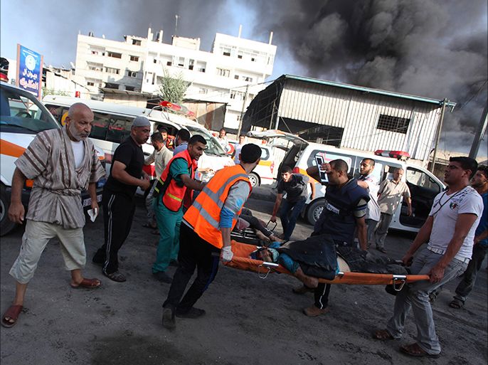 Palestinians carry the body of a local Palestinian journalist, whom medics said was killed by Israeli shelling near a market in Shejaia, as smoke rises in the east of Gaza City July 30, 2014. Israeli strikes near a market in the eastern Gaza Strip killed 15 Palestinians on Wednesday, the local health ministry said. Residents said that Israeli shelling and two missiles from the air hit the area in Shejaia, on the fringes of the city of Gaza. Ashraf al-Qidra, spokesman of the Gaza Health Ministry, said 160 people were also wounded. An Israeli military spokeswoman said she was checking the report. Israel launched its offensive in response to rocket salvoes fired by Gaza's dominant Hamas Islamists and their allies. REUTERS/Ashraf Amrah (GAZA - Tags: POLITICS CIVIL UNREST MEDIA) TEMPLATE OUT