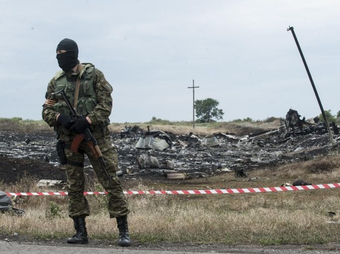 A pro-Russian fighter guards the crash site of a Malaysia Airlines jet near the village of Hrabove, eastern Ukraine, Saturday, July 19, 2014. Ukraine accused Russia on Saturday of helping separatist rebels destroy evidence at the crash site of a Malaysia Airlines plane shot down in rebel-held territory — a charge the rebels denied. (AP Photo/Evgeniy Maloletka)