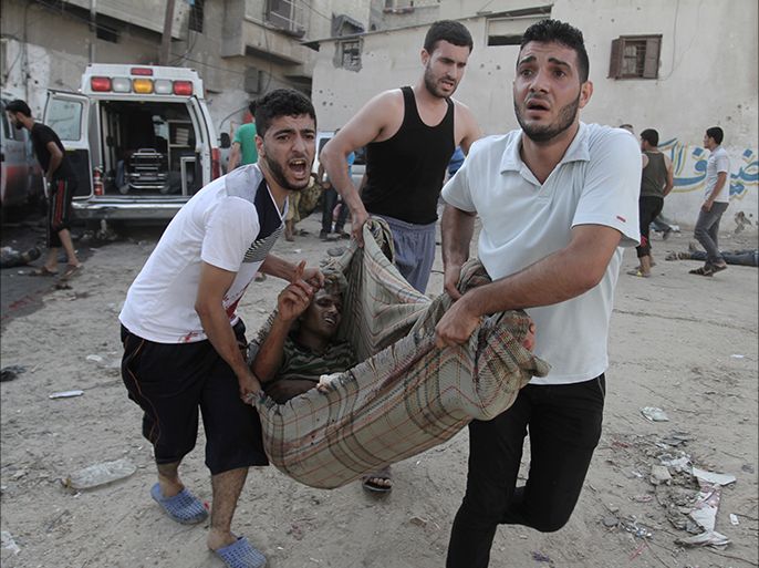epa04335703 Palestinians carry a man who was wounded during an Israeli airstrike on a market place in the Shejaiya neighbourhood near Gaza City, 30 July 2014. On the 23rd day of the Israeli offensive in Gaza the death toll there has reached 1,283. More than 7,150 people have been wounded. EPA/SAMEH RAHMI