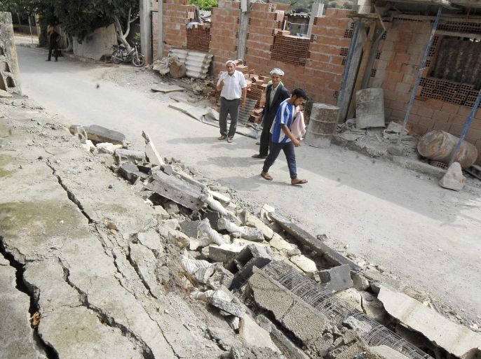 Residents walk in a damaged street after a quake hit Hamam Melounane, near Blida, Algeria, early Wednesday, July 17, 2013. A magnitude 5.1 earthquake hit an area south of the Algerian capital, injuring more than 10 people and causing minor damage to buildings. (AP Photo/Sidali Djarboub)