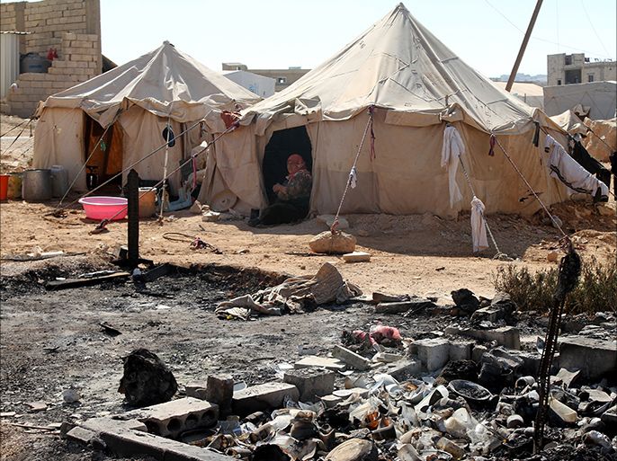 epa04347409 A Syrian refugee woman sits in front her tent amid damage and the remains of tents at a refugee camp that was burnt during clashes between the army and Islamist militants at the Lebanese town of Arsal near the Syrian border in Bekaa Valley, Lebanon, 09 August 2014, a day after the Lebanese army began deploying into the town. The fighting, which started in the north-eastern town on 02 August, has left stranded an estimated 40,000 locals and as many as 120,000 Syrian refugees, according to Lebanese media. Spurred by the fighting, which has left some of their number dead, a group of 1,700 Syrian refugees who had been based in Arsal opted to return to their home country. The Lebanese army secured their departure, helping them head towards the Masnaa border crossing. EPA/STR