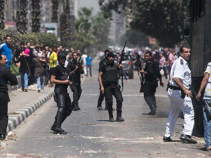 Egyptian policemen stand in the middle of al-Haram street in Cairo on August 14, 2014, during clashes with Muslim Brotherhood supporters following a rally marking the first anniversary of a brutal Cairo crackdown. On August 14, 2013, after then army chief and now President Abdel Fattah al-Sisi had removed Egypt's first freely elected president Mohamed Morsi, the security forces cracked down on thousands of Morsi supporters at protest camps in Rabaa al-Adawiya and Nahda squares, leaving more than 700 people dead according to official estimates. AFP PHOTO / MOHAMED El-SHAHED