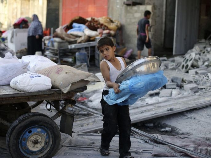 A Palestinian boy carries belongings near his family's damaged house, which witnesses said was hit by an Israeli air strike, in Rafah in the southern Gaza Strip August 26, 2014. Israeli air strikes launched before dawn on Tuesday killed two Palestinians and destroyed much of one of Gaza's tallest apartment and office buildings, setting off huge explosions and wounding 20 people, Palestinian health officials said. Israel had no immediate comment on the attacks that took place as Egyptian mediators stepped up efforts to achieve an elusive ceasefire to end seven weeks of fighting. Israel launched an offensive on July 8, with the declared aim of ending rocket fire into its territory. REUTERS/Ibraheem Abu Mustafa (GAZA - Tags: POLITICS CIVIL UNREST)