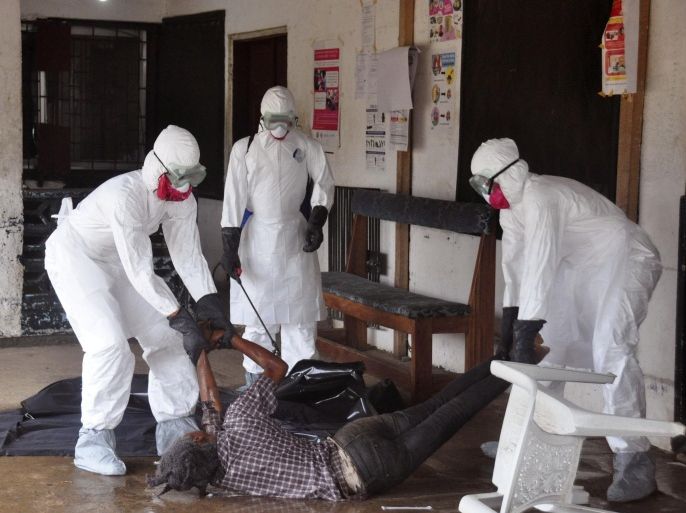 Health workers in protective gear move the body of a person that they suspect dyed form the Ebola virus in Monrovia, Liberia, Tuesday, Sept. 16, 2014. The number of Ebola cases in West Africa could start doubling every three weeks and it could end up costing nearly $1 billion to contain the crisis, the World Health Organization warned Tuesday. (AP Photo/Abbas Dulleh)