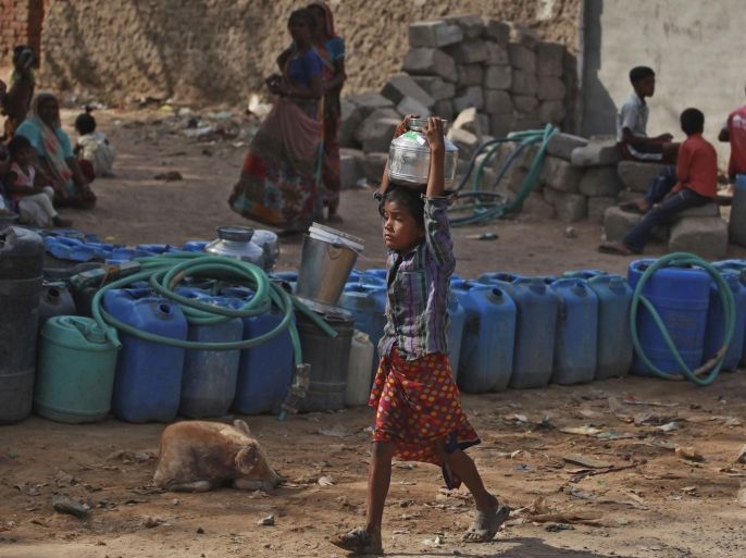 A young Indian girl walks carrying water as others wait for a municipal water tanker to arrive in Ramol, outskirts of Ahmadabad, India, Sunday, May 11, 2014. As India faces certain water scarcity and ecological decline, the country's main political parties campaigning for elections have all but ignored environmental issues seen as crucial to India's vast rural majority, policy analysts say. With 814 million eligible voters, India’s weeks long general election runs through May 12, with results for the 543-seat lower house of Parliament set to be announced May 16. (AP Photo/Ajit Solanki)