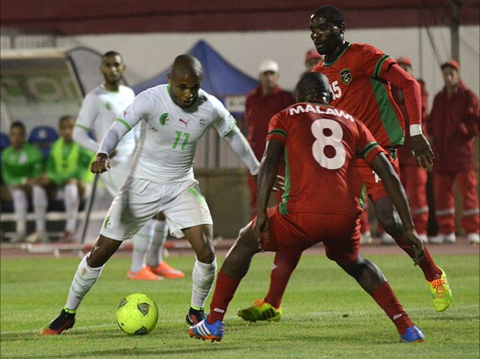 Algeria's Yacine Brahimi (L) vies with Malawi's Phillip Masiye (C) during the 2015 Africa Cup of Nations qualifying football match between Algeria and Malawi at the Mustapha Tchaker stadium on October 15, 2014 in Blida. AFP PHOTO / STR