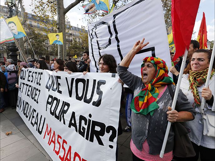 People hold a banner reading ''What are you waiting for to act? a new massacre'' as they wave flags of the jailed leader of Turkey's outlawed Kurdistan Workers Party (PKK) Abdullah Ocala during a protest to show support to Kurdish people living in the Syrian town of Kobane on October 11, 2014 in Paris. Kurdish fighters halted a thrust by Islamic State group jihadists towards the heart of the battleground Syrian town of Kobane, after the UN warned thousands of civilia