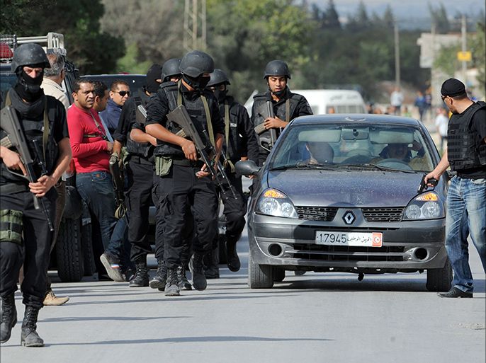 Members of the Tunisian national guard are deployed outside a house where gunmen had taken refuge in the town of Oud Ellil, a few kilometres from the capital, after exchanging fire with the armed group on October 23, 2014. The suspects were arrested after killing a private security guard in the gunfight, the interior ministry spokesman Ali Aroui said. AFP PHOTO / FETHI BELAID