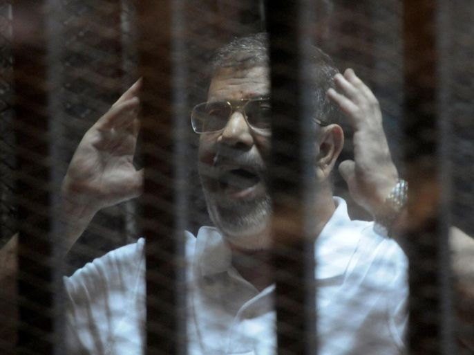 Egypt's deposed Islamist president Mohamed Morsi gestures inside the defendants cage during his trial at the police academy in Cairo on October 14, 2014. Morsi is on trial in several cases and faces a death sentence if convicted of espionage and terrorism related charges. AFP PHOTO / STR