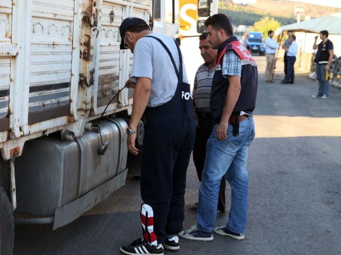FILE - In this Saturday, Sept. 20, 2014 file photo, Turkish anti-smuggling experts check a truck on a road near Hacipasa, Hatay, Turkey. At the peak of Turkey’s oil smuggling boom, the main transit point was a dusty hamlet called Hacipasa on the Orontes River that marks the border with Syria. Hacipasa has been a smuggling haven for decades, authorities and residents say. The fuel had come from oil wells in Iraq or Syria controlled by militants, including the Islamic State group, and was sold to middle men who smuggled it across the Turkish-Syrian border.(AP Photo/Burhan Ozbilici, File)