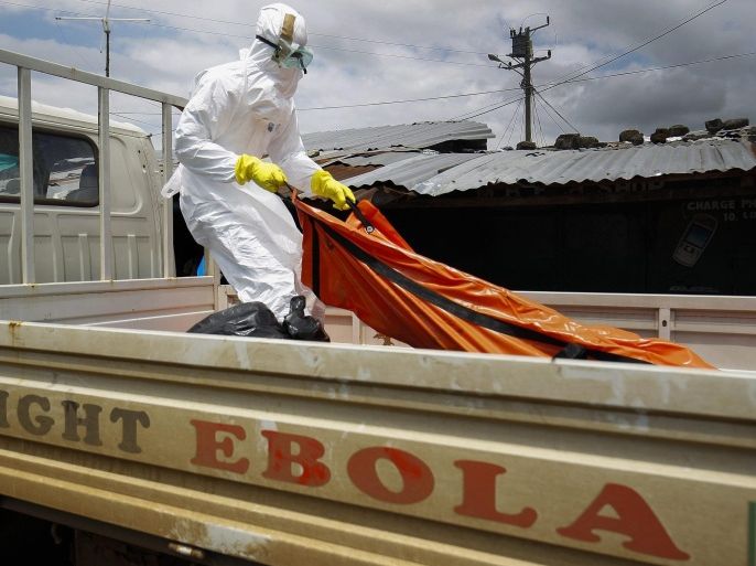 A Liberian Red Cross burial team member picks up the body of a suspected Ebola victim onto a truck in the impoverished area of West Point, Monrovia, Liberia, 15 October 2014. Latest statistics from the United Nations World Health Organization (WHO) place the death toll from the Ebola virus outbreak at 4,447 with most of those fatalities in West Africa.