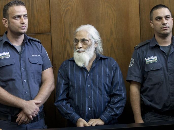 Flanked by security personnel, Goel Ratzon, a polygamist cult leader, attends a hearing in the district court room in Tel Aviv, Israel, Monday, Sept. 8, 2014. The Israeli court convicted Ratzon Monday on several accounts of sex crimes against the harem of women he maintained, including rape, incest and other offenses. Ratzon kept at least 21 "wives" whom were kept in a state of near total obedience. (AP Photo/Moti Milrod, Pool)