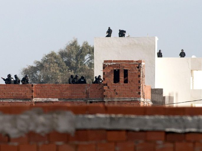 ALTERNATIVE CROP OF TUN106 - Tunisian anti-terrorist police forces (BAT) stand on roofs near a house where suspected Islamist militants were hidden in Raoued, near Tunis, Tuesday, Feb.4, 2014. Tunisia’s National Guard stormed suspected militants in two houses in a seaside suburb of Tunis on Tuesday to end a daylong standoff, and seven radicals and one member of the security force were killed. The firefight began Monday afternoon when National Guard anti-terrorist units surrounded a house believed to contain militants in the Raoued suburb. (AP Photo/Aimen Zine)