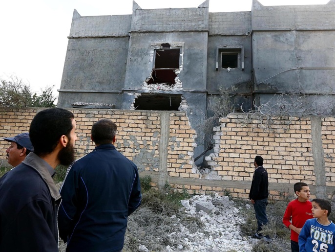 مدنيون يتفقدون أحد المباني التي تعرضت للقصف قرب مطار معيتيقة(غيتي)
