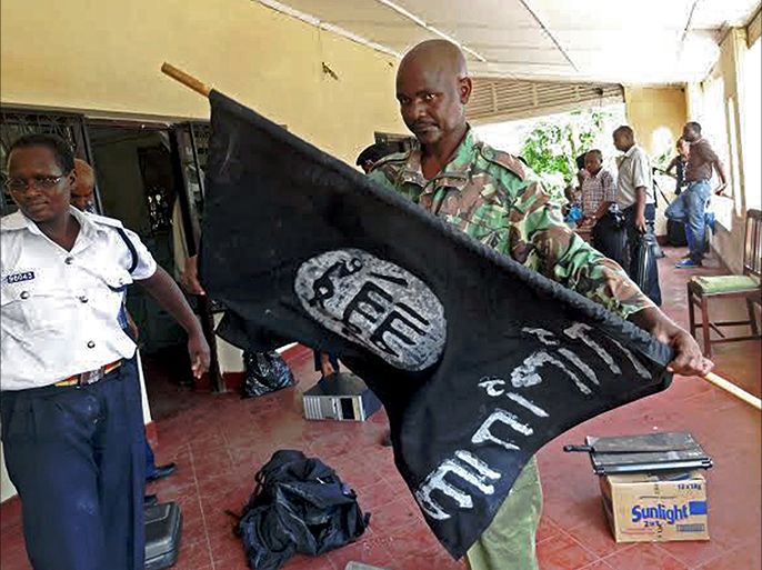A Kenyan police officer folds up a flag inscribed with the logo of the Islamic state (IS) following a raid on two mosques in the coastal city of Mombasa, on November 17, 2014. One man was killed as Kenyan security forces arrested over 200 people and seized weapons in raids on mosques accused of links with Somalia's Al-Qaeda affiliated Shebab militants, police said. Security forces began the operation in the early hours of Monday morning, targeting the Masjid Musa and Sakina mosques in the port city of Mombasa. AFP PHOTO/STR