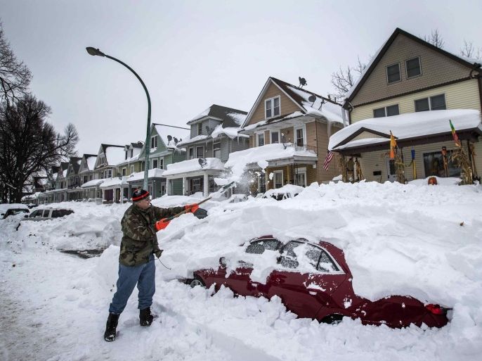 Thomas Wisniewki digs his car out of snow following a massive snow storm in Buffalo, New York November 22, 2014. Warm temperatures and rain were forecast for the weekend in the city of Buffalo and western New York, bringing the threat of widespread flooding to the region bound for days by deep snow. REUTERS/Mark Blinch (UNITED STATES - Tags: ENVIRONMENT)