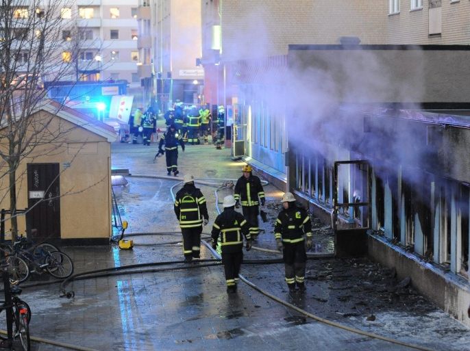 Firemen work outside a still smoking cellar mosque in Eskilstuna, Sweden, 25 December 2014. Five of the twenty at prayer inside were taken to hospital after inhaling smoke when a burning object was hurled through a window,  setting fire to the building in the early afternoon.  EPA/PONTUS STENBERG  SWEDEN OUT