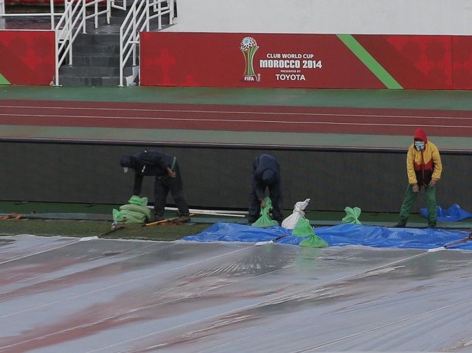 Workers clean the covered field after heavy rain at the Complexe Sportif Prince Moulay Abdellah, during the Club World Cup soccer tournament, in Rabat, Morocco, Sunday, Dec. 14, 2014. Due to difficult pitch conditions, the FIFA Organising Committee has decided, following consultation with the Local Organising Committee (LOC), to play match 4 (Cruz Azul FC v. Real Madrid CF) in Marrakech and not in Rabat as previously scheduled. (AP Photo/Christophe Ena)