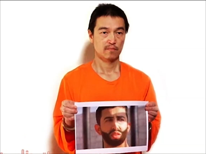 ‪(الجزيرة)‬ كينجي غوتو يحمل صورة الطيار الكساسبة خلال رسالة نقلها تنظيم الدولة على لسانه