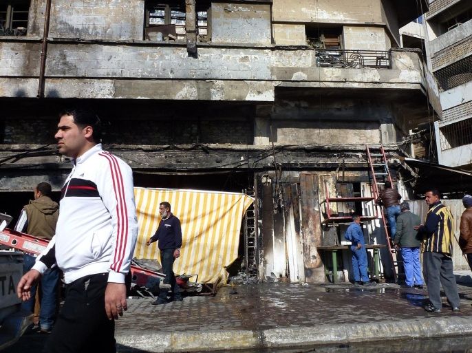 Men walk past the front of a building damaged in an explosion the day before at a market in Baghdad on January 31, 2015. At least one bomb exploded in a used clothes market in the central Bab al-Sharji area, killing at least five people and wounding 17, officials said. AFP PHOTO / SABAH ARAR