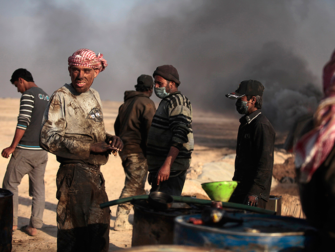 ‪سوريون يعملون على تكرير النفط الخام بطريقة بدائية في ريف الرقة‬ (رويترز)