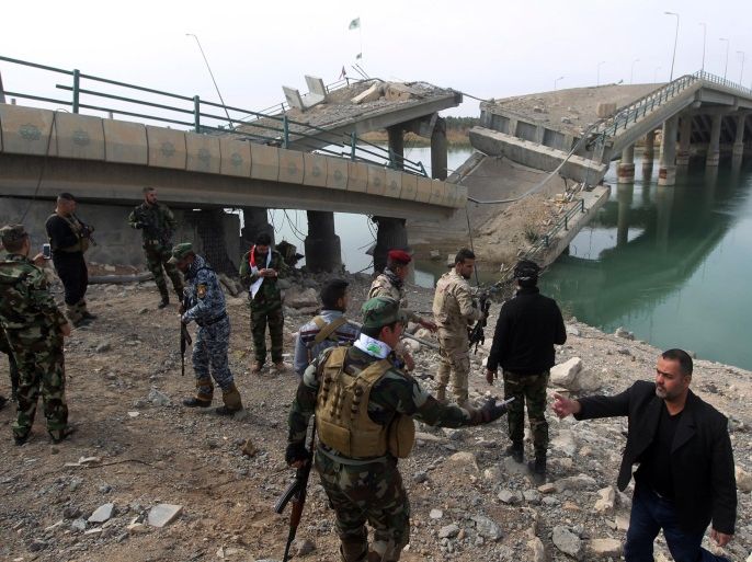 Volunteer Shiite fighters who support the government forces in the combat against the Islamic State (IS) group stand next to a destroyed bridge that connects the southwestern city of Fallujah with Baghdad on the oustkirts of the village of Fadhiliyah, which pro-government forces retook from IS militants the previous month, on the road leading to Fallujah, in Iraq's flashpoint Anbar province, southwest of the capital, on February 24, 2015. The government forces lost control of parts of Anbar's provincial capital Ramadi and all of Fallujah at the beginning of 2015 to anti-government fighters. AFP PHOTO / AMHAD AL-RUBAYE