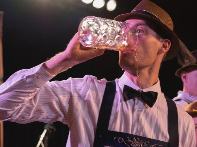 Oktoberfest celebrations in Toronto, Ontario, Canada. Man drinks a whole mug of beer as it spills on the sides of his mouth.