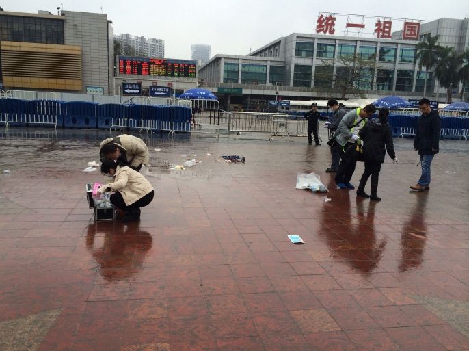 WH1232 - Guangzhou, Guangdong, CHINA : Investigators check the scene after a knife attack happened at the main station in Guangzhou, south China's Guangdong province on March 6, 2015. A man was shot dead by police and another detained after a knife attack at a Chinese train station which left nine people wounded on March 6, police said. CHINA OUT AFP PHOTO