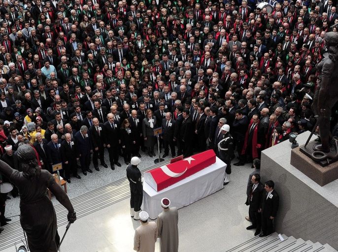 People stand on April 1, 2015 in Istanbul near the coffin of senior Istanbul prosecutor Mehmet Selim Kiraz, killed the day before after being held at his offices by leftist militants in a hostage drama, during a funeral ceremony inside of the courthouse where the hostage taking took place. Kiraz had been investigating the politically-sensitive case of a teenager who died of injuries inflicted by police during anti-government protests in 2013. Turkish authorities on April 1 rounded up over 30 suspected members of the radical leftist group behind a bloody hostage standoff that left a top Istanbul prosecutor dead and shocked the country. AFP PHOTO / OZAN KOSE