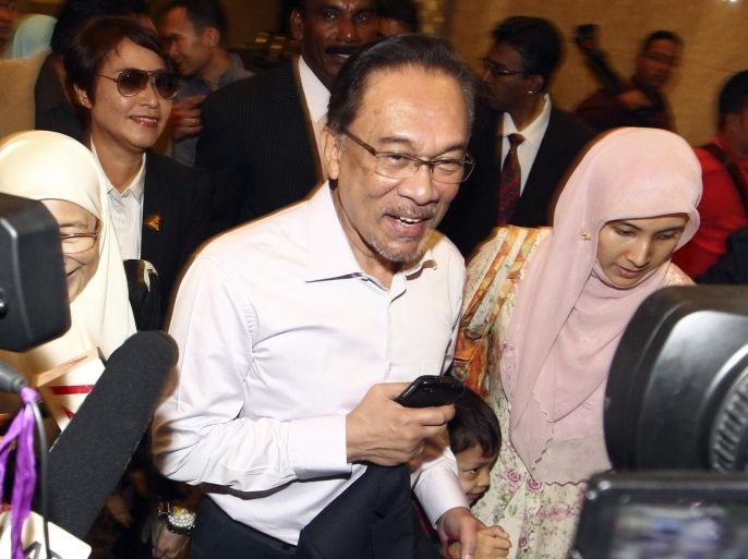 FILE - In this Tuesday, Feb. 10, 2015 file photo, Malaysian opposition leader Anwar Ibrahim, center, arrives at court house in Putrajaya, Malaysia. Ibrahim began a 5-year prison sentence on Feb. 10 after being found guilty of sodomizing a former male aide in 2008. (AP Photo/File) MALAYSIA OUT