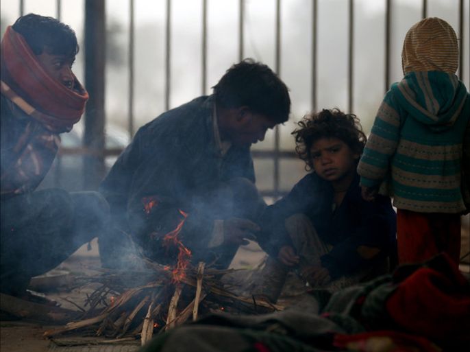 epa04538553 Indian people sit around a fire during a cold winter morning in New Delhi, India, 23 December 2014.