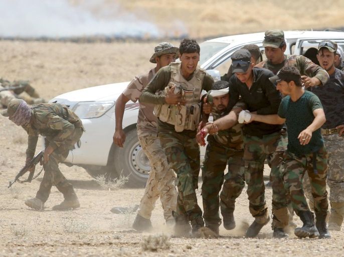Iraqi Shi'ite paramilitaries help a wounded fighter after clashes with Islamist State militants in al Nibaie, in Anbar province May 26, 2015. Iraq's Shi'ite paramilitaries said on Tuesday they had taken charge of the campaign to drive Islamic State from the western province of Anbar, giving the operation an openly sectarian codename that could infuriate its Sunni Muslim population. REUTERS/Stringer