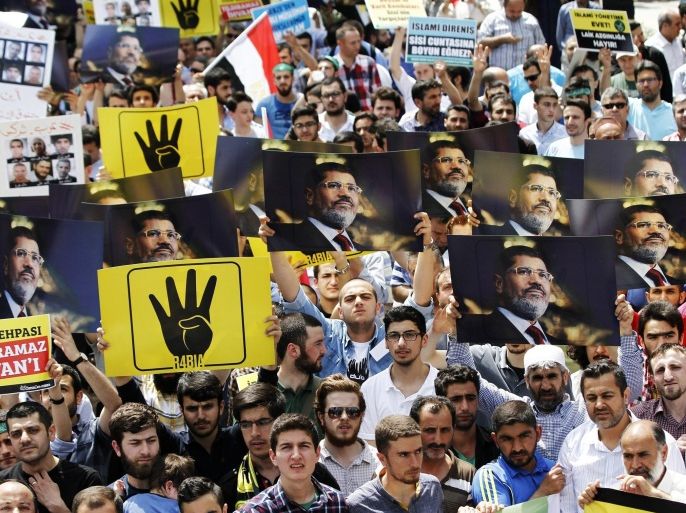 People hold pictures of Mohamed Morsi and the four fingered salute associated with the killing of Muslim Brotherhood supporters August 2013 during a protest against an Egyptian court's decision to seek the death sentence for deposed Egyptian President, Mohamed Morsi, Istanbul, Turkey, 17 May 2015. Turkey has held a critical position toward Egypt since Mohamed Morsi was deposed by the Egyptian military July 2013, and following a court decision to seek the death sentence for Morsi on charges of a 2011 prison break 16 May, Erdogan heavily criticised the incumbent regime of Abdel Fattah al-Sisi and the West for its lack of response to the sentence.