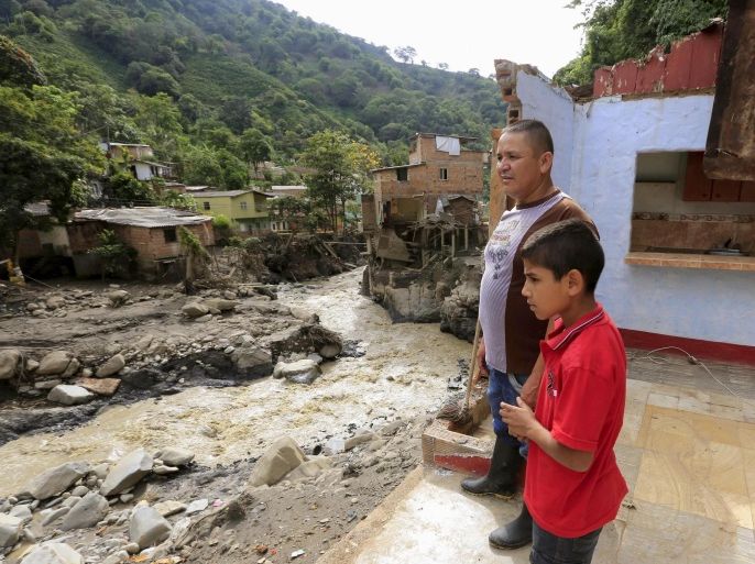 Manuel Cano and his nephew stand inside a house damaged during the recent landslide in the municipality of Salgar in Antioquia department, Colombia May 20, 2015. The landslide sent mud and water crashing onto homes in the town in Colombia's northwest mountains on Monday, killing more than 50 people and injuring dozens, officials said. REUTERS/Jose Miguel Gomez