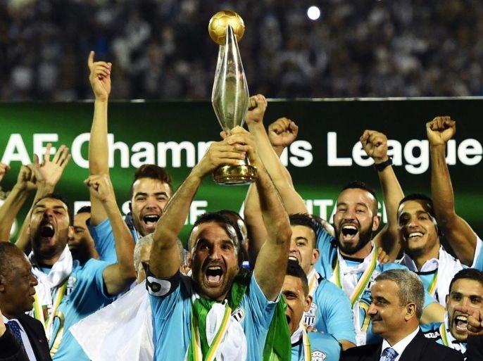 ES Setif captain Farid Mellouli holds the CAF Champions League trophy on November 1, 2014 in the Mustapha-Tchaker stadium in Blida as his team mates celebrate after the football match against the Congolese AS Vita Club. Algerians Entente Setif won the CAF Champions League Saturday despite being held 1-1 at home by Congolese V Club in the second leg of the final. AFP PHOTO/FAROUK BATICHE