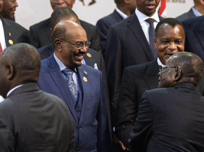 Sudanese President Omar al-Bashir (L) is greeted by African Union Chairperson and Zimabwean President Robert Mugabe (R) during a group photograph of leaders at the 25th African Union Summit in Sandton South Africa on June 14, 2015. Sudanese President Omar al-Bashir joined a group photograph of leaders at the African Union summit in Johannesburg on June 14 despite the International Criminal Court calling for him to be arrested at the event. Wearing a blue suit, he stood in the front row for the photograph along with South African host President Jacob Zuma and Zimbabwe's President Robert Mugabe, who is the chair of the 54-member group. AFP PHOTO / GIANLUIGI GUERCIA