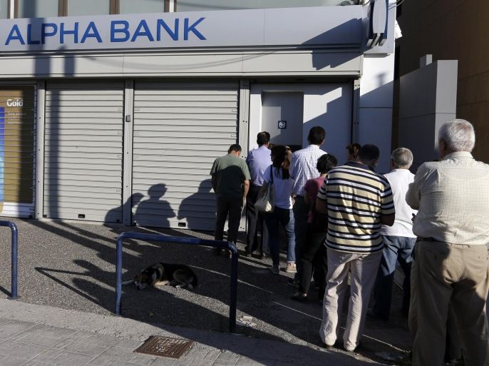 People stand in a queue to use an ATM of a bank during the referendum day voting in Athens, Sunday, July 5, 2015. Greeks began voting early Sunday in a closely-watched, closely-contested referendum, which the government pits as a choice over whether to defy the country's creditors and push for better repayment terms or essentially accept their terms, but which the opposition and many of the creditors paint as a choice between staying in the euro or leaving it. (AP Photo/Thanassis Stavrakis)