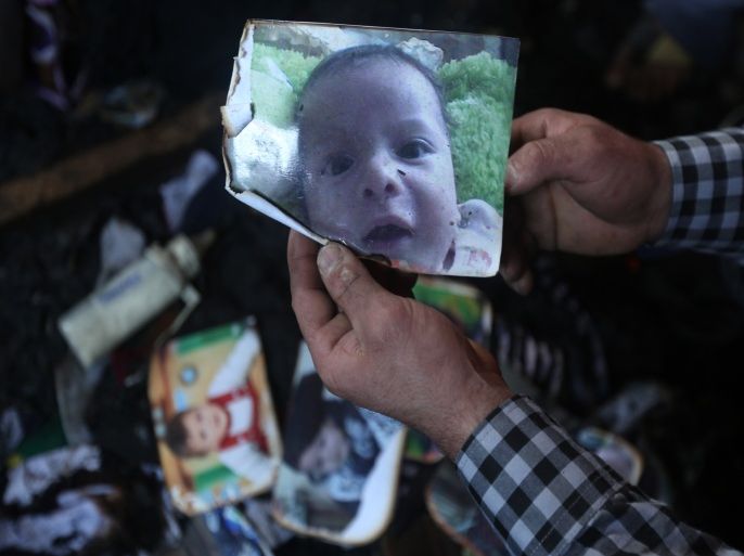 JA06 - DUMA, WEST BANK, - : A man shows a picture of 18-month-old Palestinian toddler Ali Saad Dawabsha who died when his family house was set on fire by Jewish settlers in the West Bank village of Duma on July 31, 2015. The Palestinian toddler was burned to death and four family members injured in the arson attack on two homes in the occupied West Bank. AFP PHOTO / JAAFAR ASHTIYEH