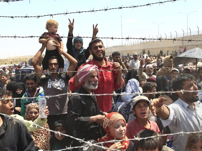 FILE - In this Monday, June 15, 2015 file photo, Syrian refugees gather at the Turkish border as they flee intense fighting in northern Syria between Kurdish fighters and Islamic State militants in Akcakale, southeastern Turkey. (AP Photo/Lefteris Pitarakis, File)