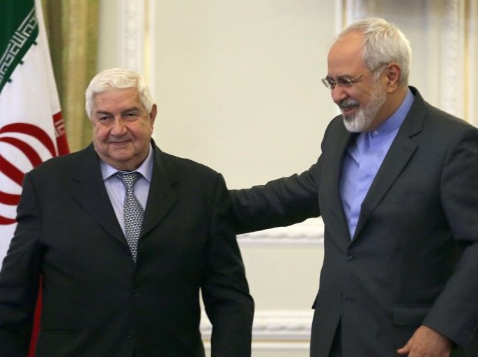 Iranian Foreign Minister Mohammad Javad Zarif (R) escorts his Syrian counterpart Walid Muallem off the podium after a press conference in Tehran on December 8, 2014, ahead of a conference with their Iraqi counterpart on combating extremism. Iran is the main regional ally of Syrian President Bashar al-Assad, and Tehran has acknowledged sending military advisers to assist his forces in their fight against armed rebels and jihadist militants. AFP PHOTO/ ATTA KENARE