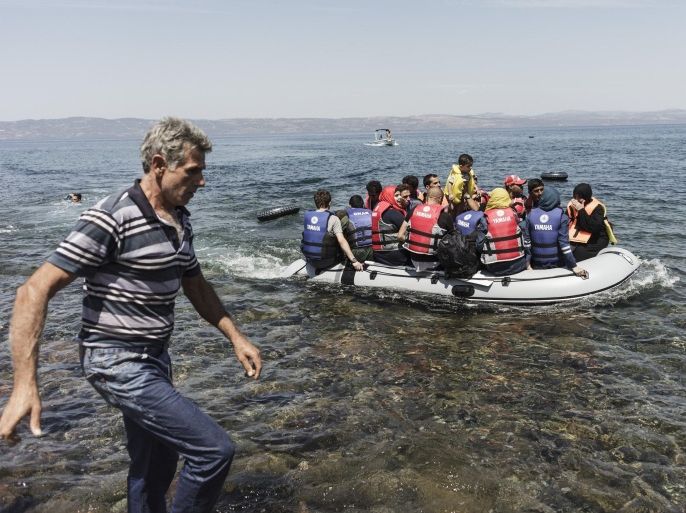 A local man (L) arrives to help migrants as they arrive on an inflatable boat on the Greek island of Lesbos after crossing the Aegean sea from Turkey to Greece on August 14, 2015. Turkish efforts to stop traffickers from sending large 'ghost ships' crammed with migrants towards Italy has sparked the surge in arrivals in Greece, the International Organization for Migration said on August 13. The migrants and refugees making the perilous journey across the Mediterranean to Europe are increasingly travelling the eastern route from Turkey to the Greek islands, which have seen more arrivals since the beginning of the year than long-time top destination Italy, according to UN figures. AFP PHOTO / ACHILLEAS ZAVALLIS