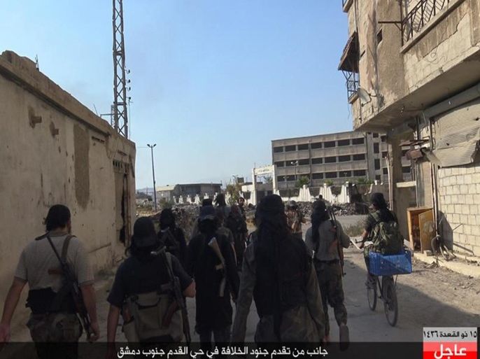 In this picture released August 30, 2015 by the Rased News Network, a Facebook page affiliated with the Islamic State group, Islamic State militants walk on a street in the Qadam neighborhood of Damascus, Syria. Islamic State fighters on Sunday pushed into a large district in southern Damascus, clashing with rival militants just a few kilometers from the center of the Syrian capital, the extremist group and Syrian activists said. Arabic at bottom reads, "Some of the Islamic State soldiers advance in the Qadam neighborhood southern Damascus." (Rased News Network, via AP)